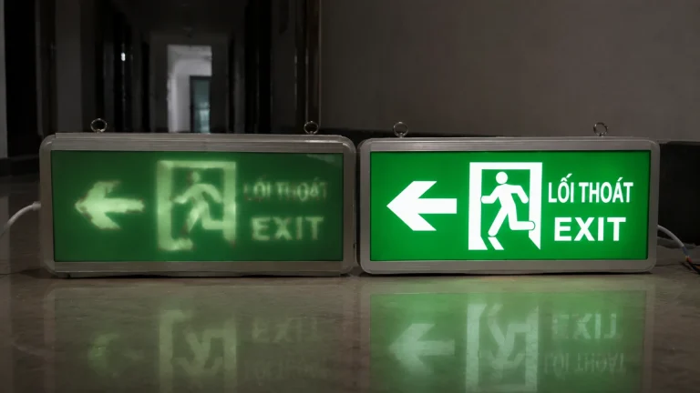 Hai đèn EXIT đặt cạnh nhau với một bên ánh sáng mờ và một bên sáng rõ dễ nhận diện