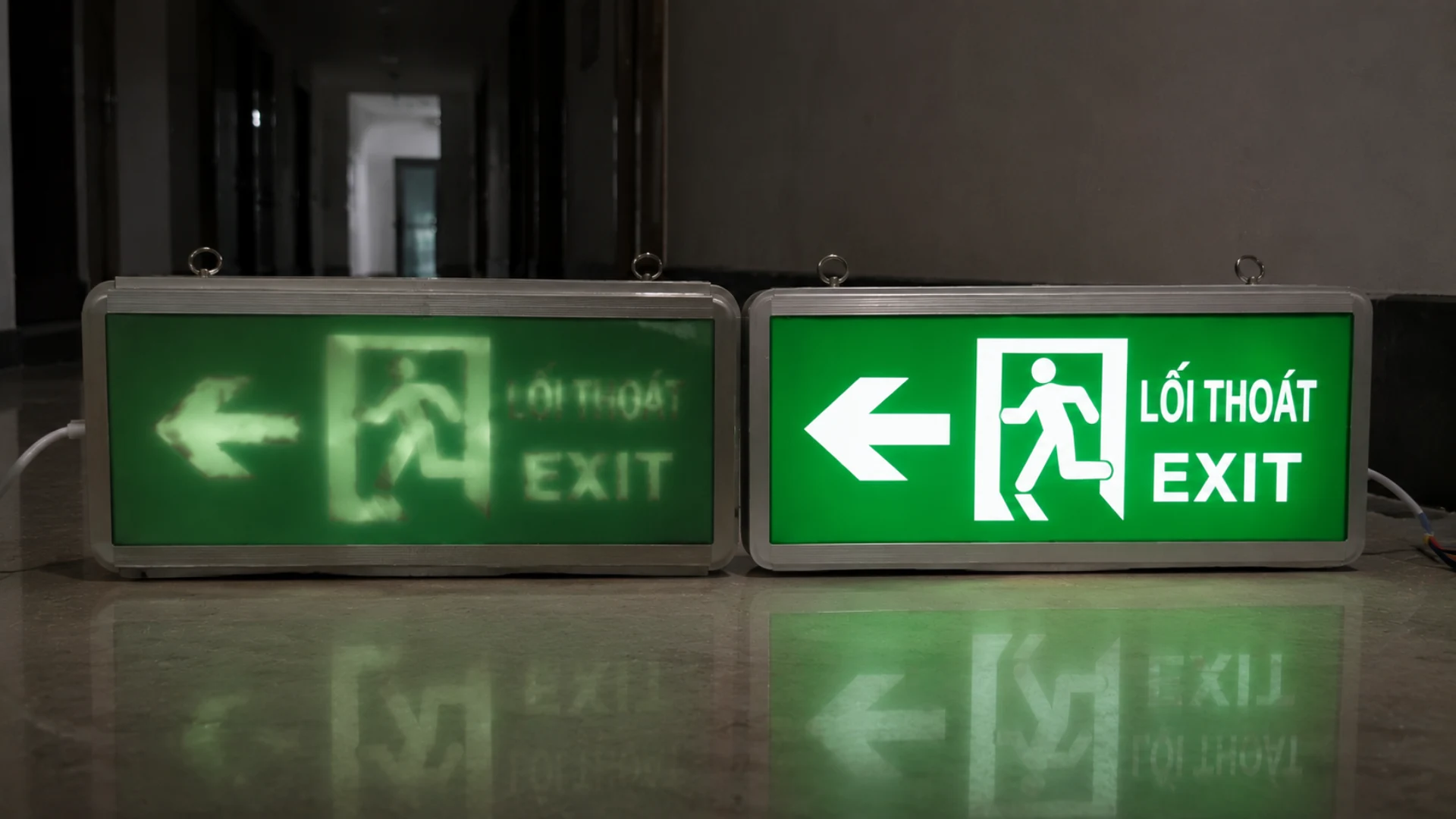 Hai đèn EXIT đặt cạnh nhau với một bên ánh sáng mờ và một bên sáng rõ dễ nhận diện