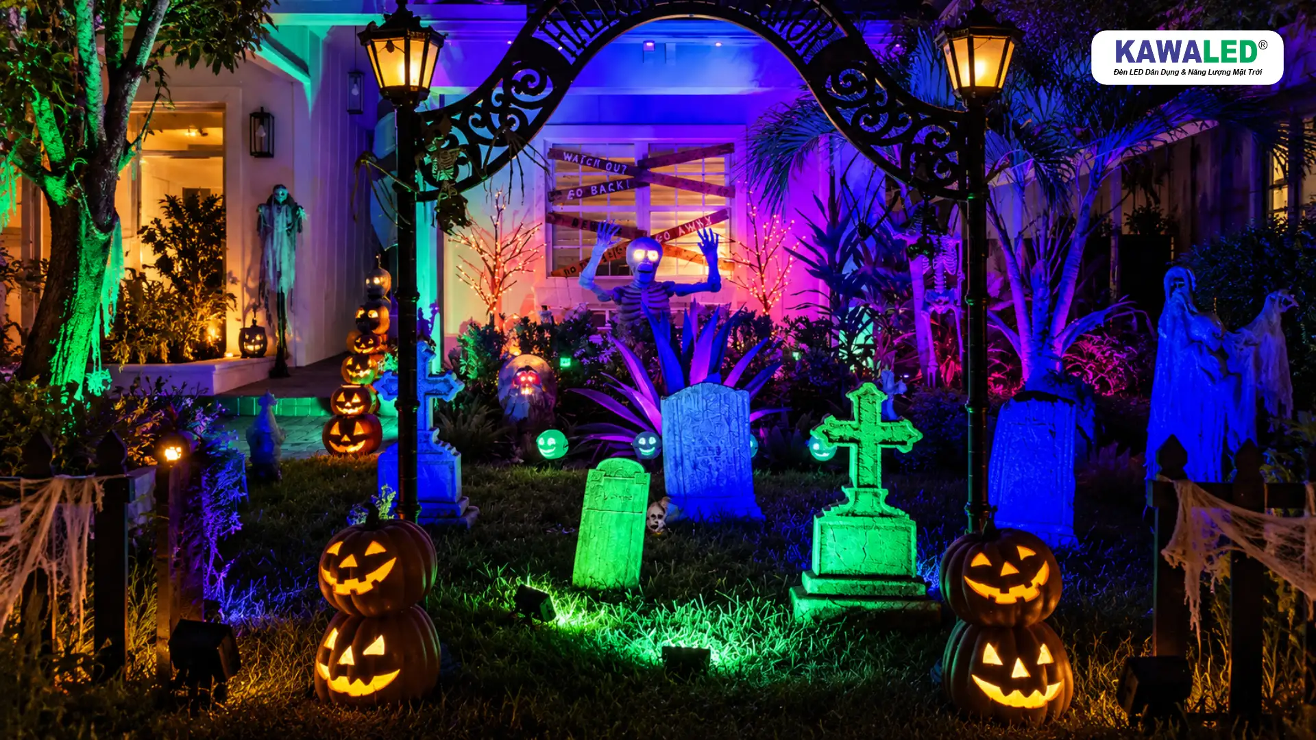 Decor Halloween ngoài trời với ánh sáng xanh dương, xanh lá và tím trên các phụ kiện trang trí.