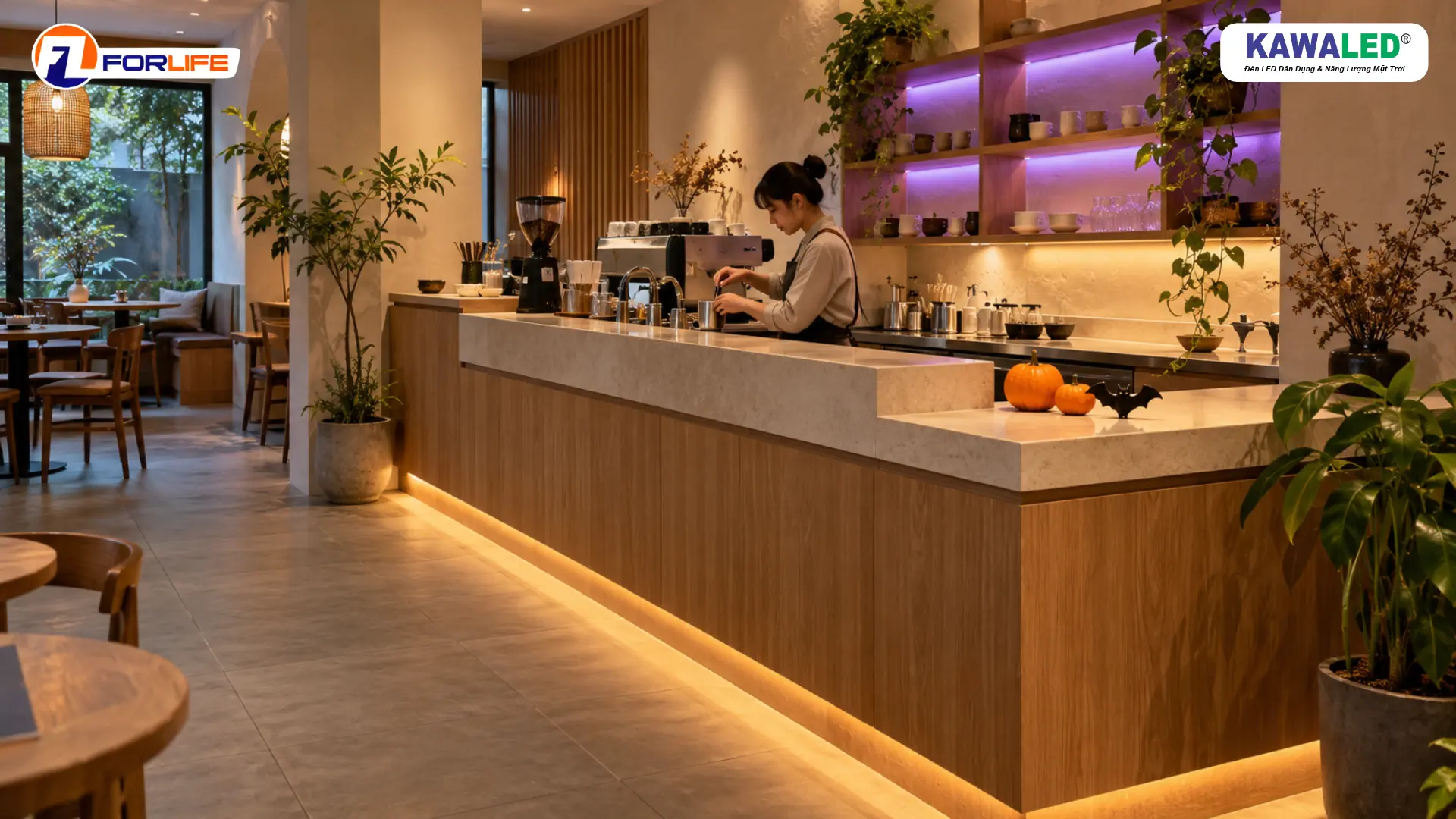 Quầy gọi món bằng gỗ có LED dây vàng dưới chân quầy, kệ phía sau ánh tím và bí ngô trên mặt đá.