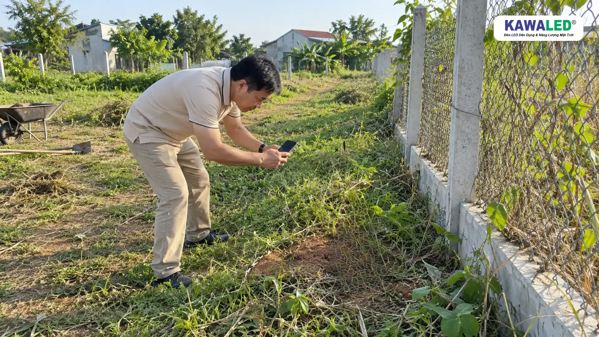 Người đàn ông sử dụng điện thoại chụp ảnh hiện trạng ranh giới khu đất chưa xây nhà.