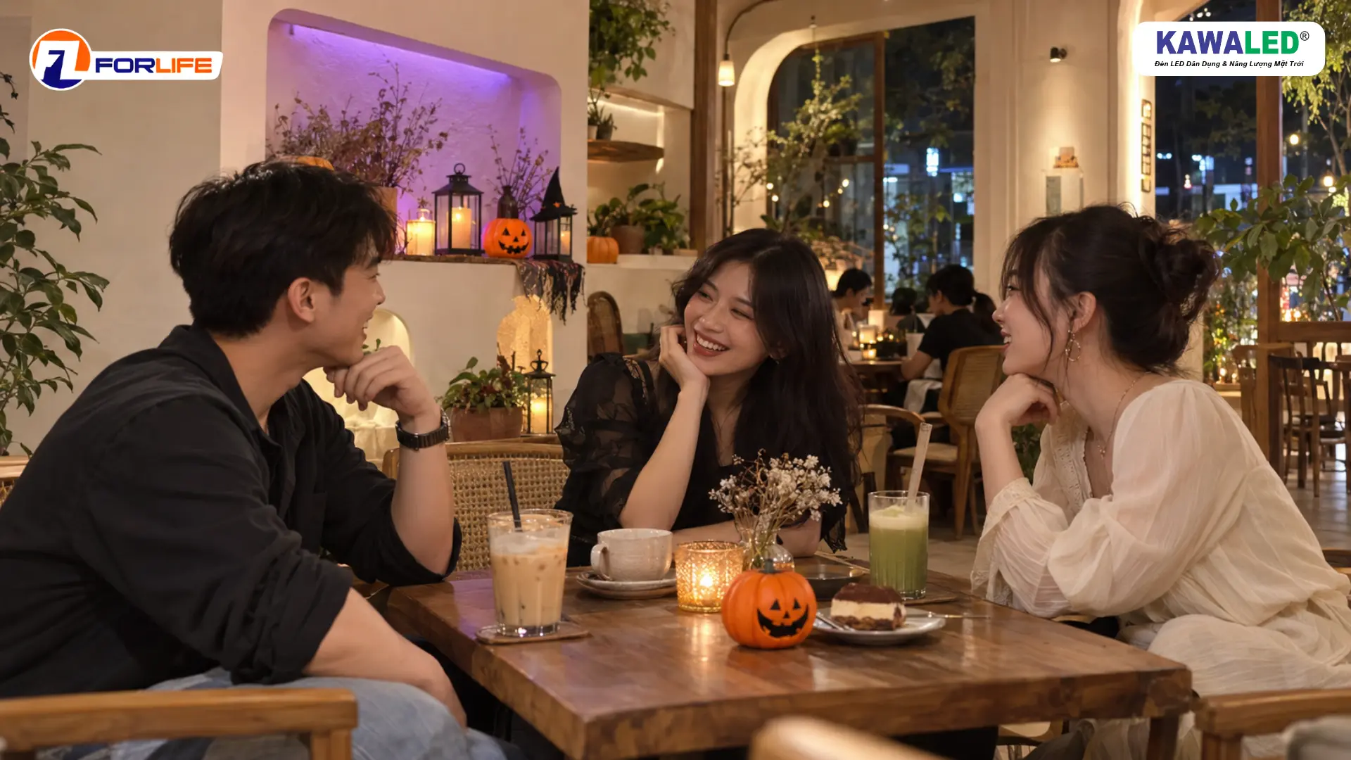 Ba người bạn trò chuyện tại bàn cà phê, phía sau là góc Halloween với bí ngô và ánh sáng tím.